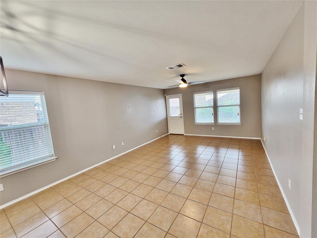 Spacious room featuring tile flooring, neutral wall tones, multiple windows with blinds, and a ceiling fan with integrated lighting Spacious room featuring tile flooring, neutral wall tones, multiple windows with blinds, and a ceiling fan with integrated lighting