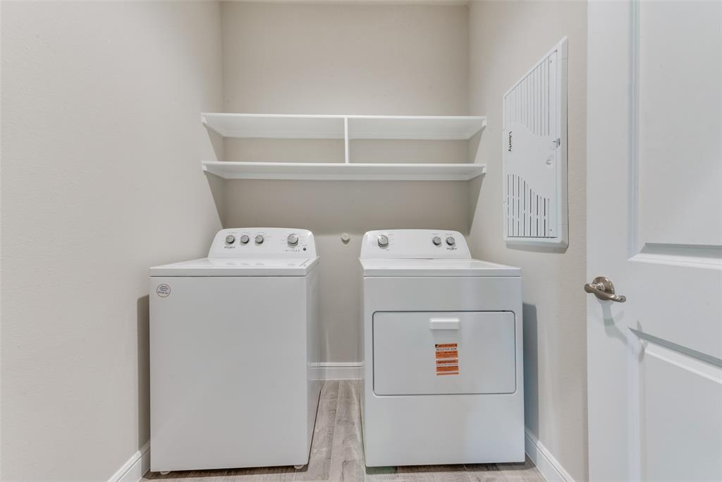 Clothes washing area featuring washing machine and clothes dryer and light hardwood / wood-style floors