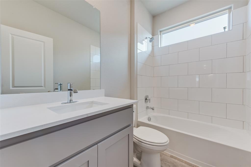 Full bathroom with hardwood / wood-style flooring, tiled shower / bath, vanity, and toilet