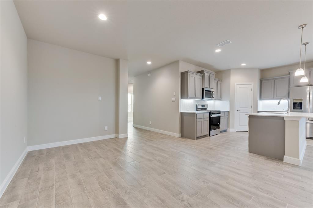 Kitchen with pendant lighting, sink, gray cabinets, light hardwood / wood-style flooring, and appliances with stainless steel finishes