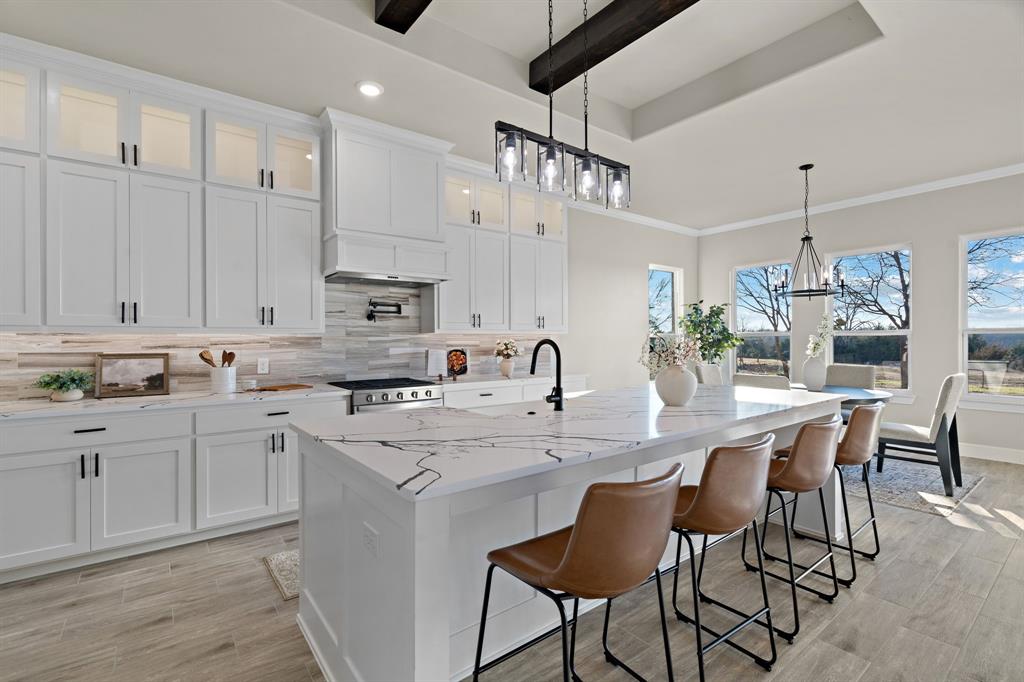 Custom cabinets with decorative lighting up top. Quartz counter tops with a gas range stove for everyday cooking.