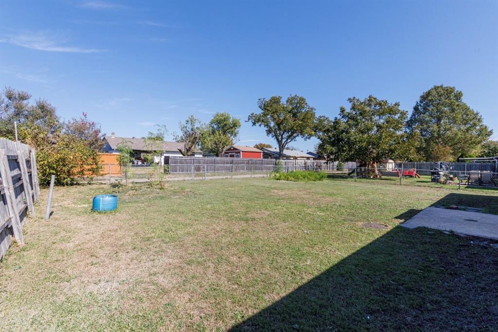 Expansive backyard featuring a large grass lawn, mature trees, concrete patio, and perimeter wood fencing