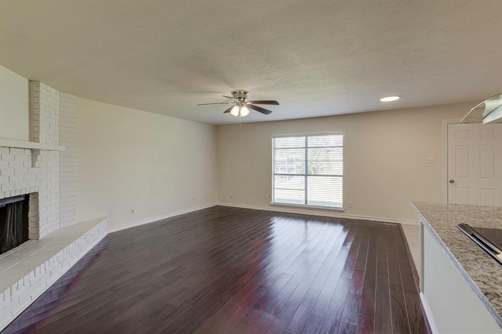 Wood-finish flooring, white painted brick fireplace with raised hearth, recessed lighting, and ceiling fan with integrated light fixture Wood-finish flooring, white painted brick fireplace with raised hearth, recessed lighting, and ceiling fan with integrated light fixture