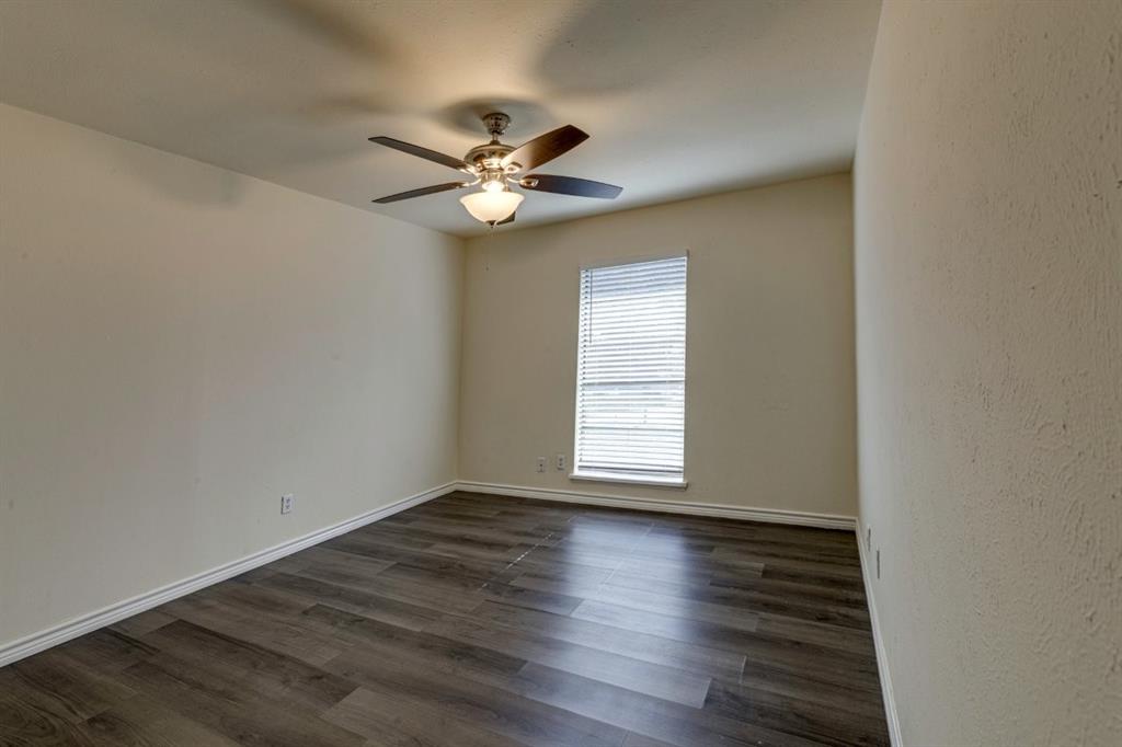 Interior room featuring wood-finish flooring, a neutral wall palette, a single window with horizontal blinds, and a multi-blade ceiling fan with an integrated light fixture