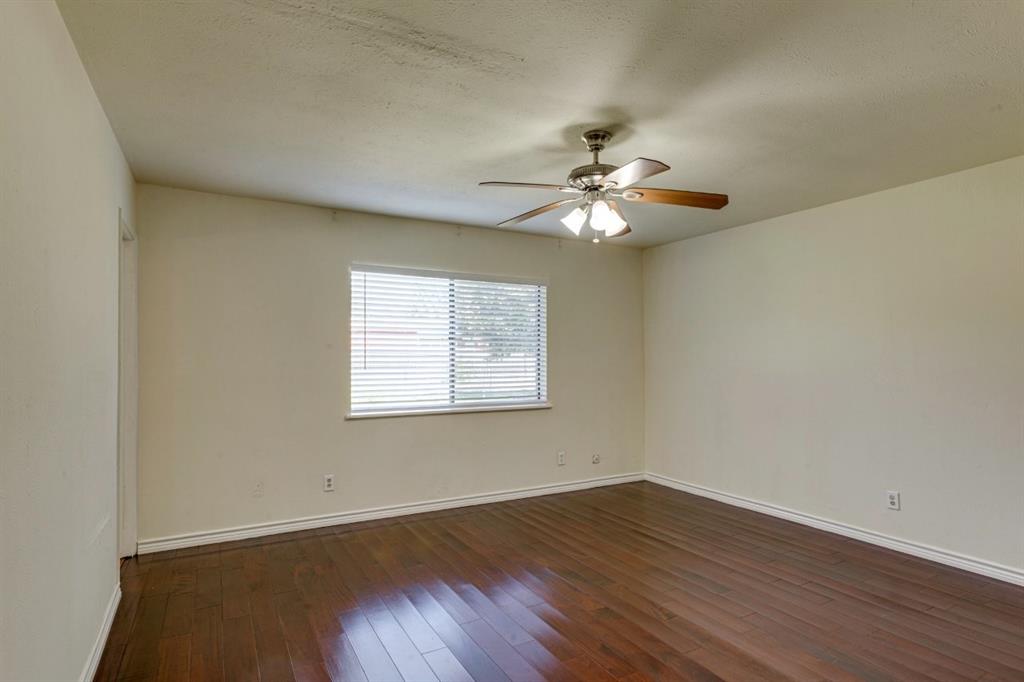 Wood-finish flooring, neutral wall tones, window with horizontal blinds, and a multi-light ceiling fan
