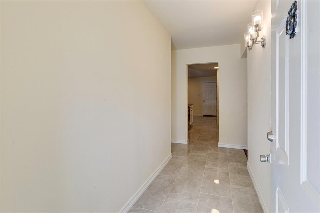 Entryway featuring large-format ceramic tile flooring, neutral wall tones, and a wall-mounted multi-bulb light fixture