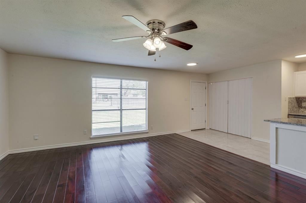Interior space featuring dark wood-finish flooring, a ceiling fan with integrated lighting, a large window with horizontal blinds, and tile flooring near the built-in storage closets Interior space featuring dark wood-finish flooring, a ceiling fan with integrated lighting, a large window with horizontal blinds, and tile flooring near the built-in storage closets