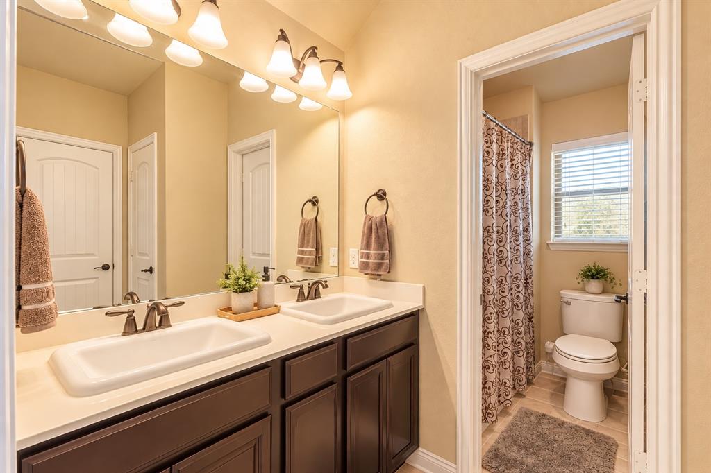 Double vanity with dark wood-finish cabinetry, dual undermount sinks, and bronze-finish faucets