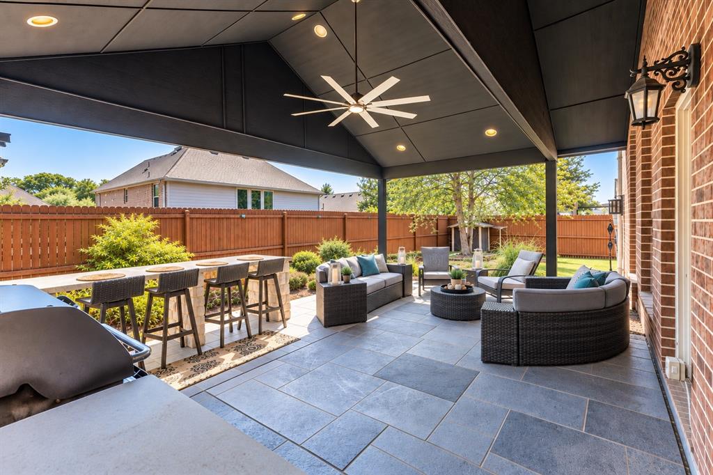 Covered outdoor patio featuring a ceiling fan with integrated lighting, recessed lighting, and large format stone-finish tile flooring