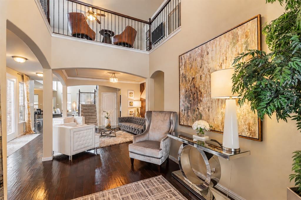 Double-height entry with dark wood-finish flooring, an open loft area with iron balusters, and arched doorways Double-height entry with dark wood-finish flooring, an open loft area with iron balusters, and arched doorways