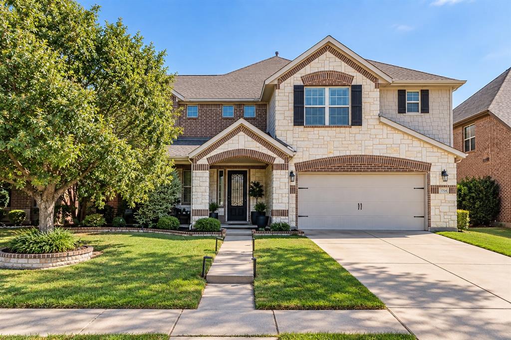 Two-story exterior with stone and brick facade accents, arched entry, attached garage, and landscaped front yard Two-story exterior with stone and brick facade accents, arched entry, attached garage, and landscaped front yard