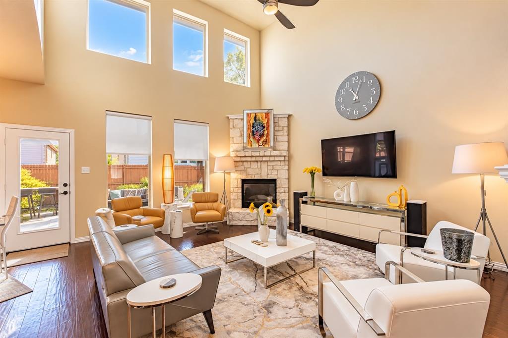 Two-story living area featuring a stone fireplace, wood-finish flooring, and a ceiling fan