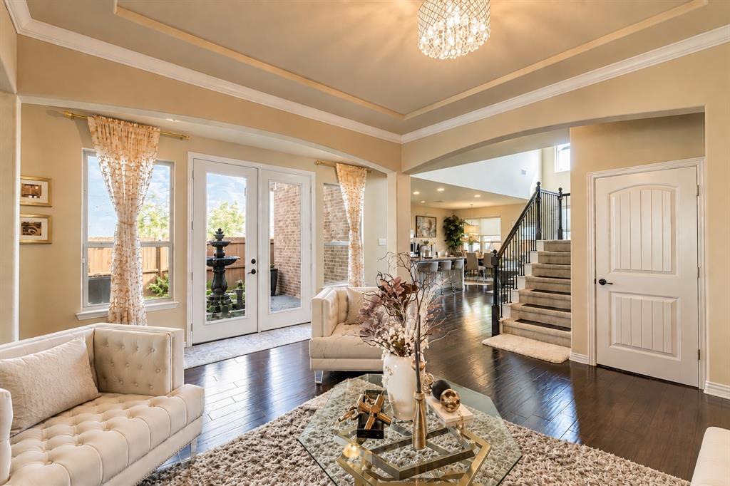 Hardwood-finish flooring, recessed tray ceiling, built-in staircase, French doors, and an arched entryway