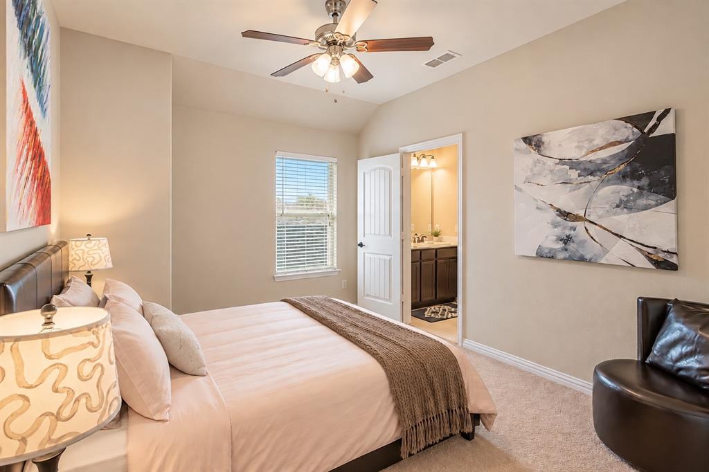 Carpeted bedroom with a built-in ceiling fan, single window with blinds, and an attached three-piece bathroom featuring a dark wood-finish vanity with a single sink