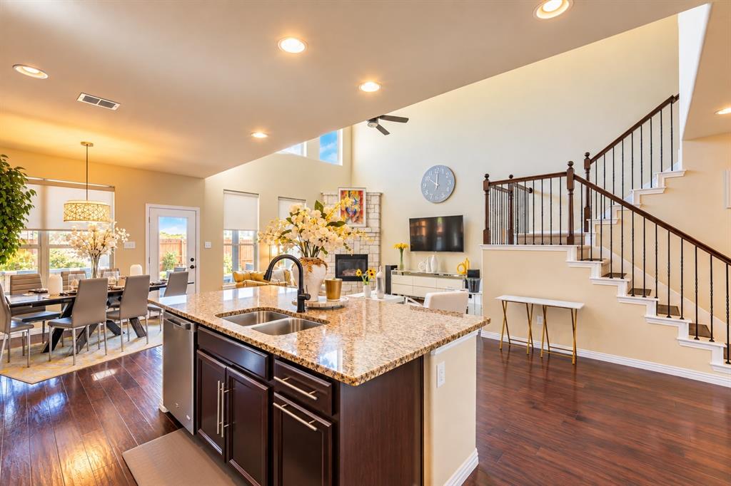 Kitchen island with granite countertop, integrated sink, and dark wood cabinetry