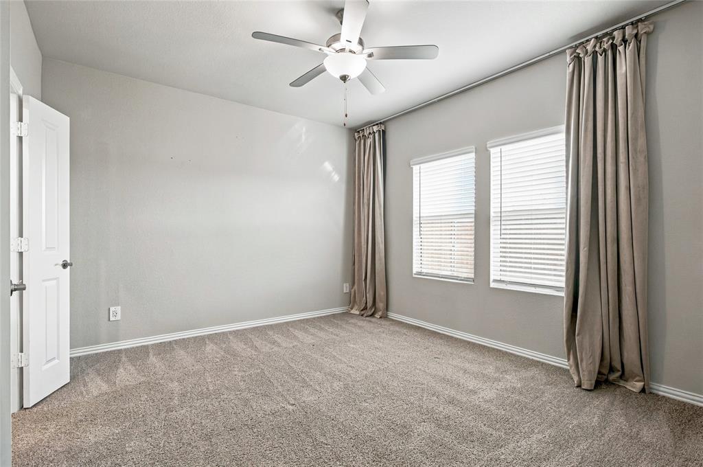 Carpeted room with neutral walls, white trim, and a ceiling fan