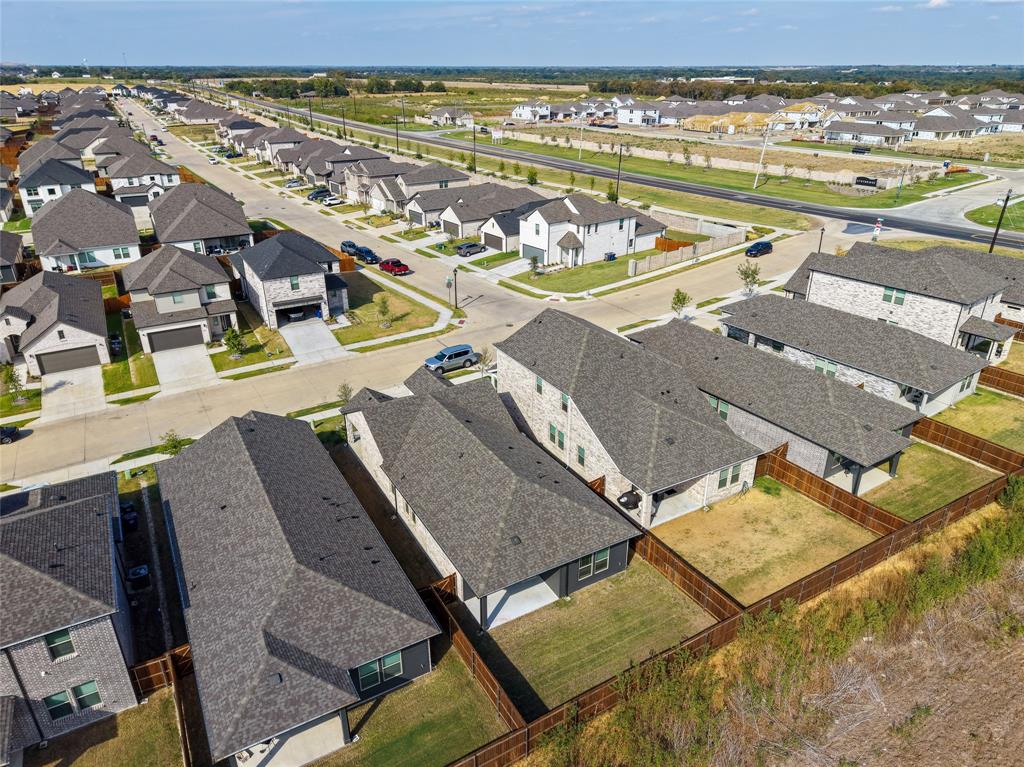 Residential neighborhood street with multiple two-story homes, brick and siding exteriors, attached garages, and fenced backyards