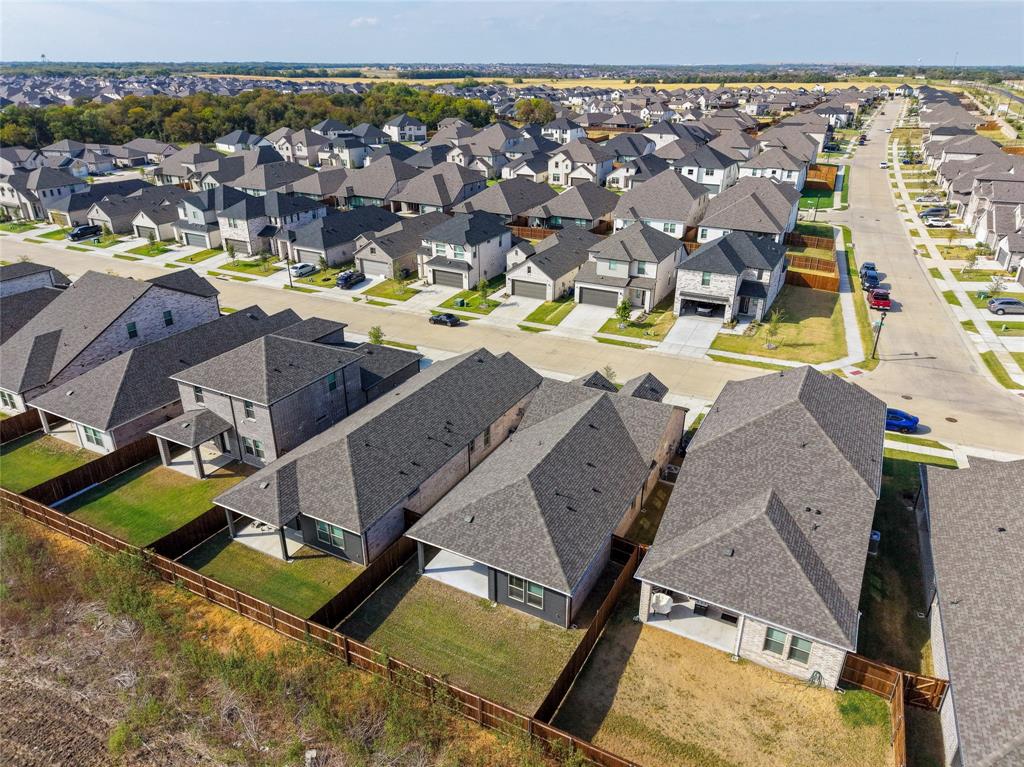 Aerial perspective of a residential neighborhood featuring multiple single-family homes with gray shingle roofs, private fenced yards, and concrete driveways