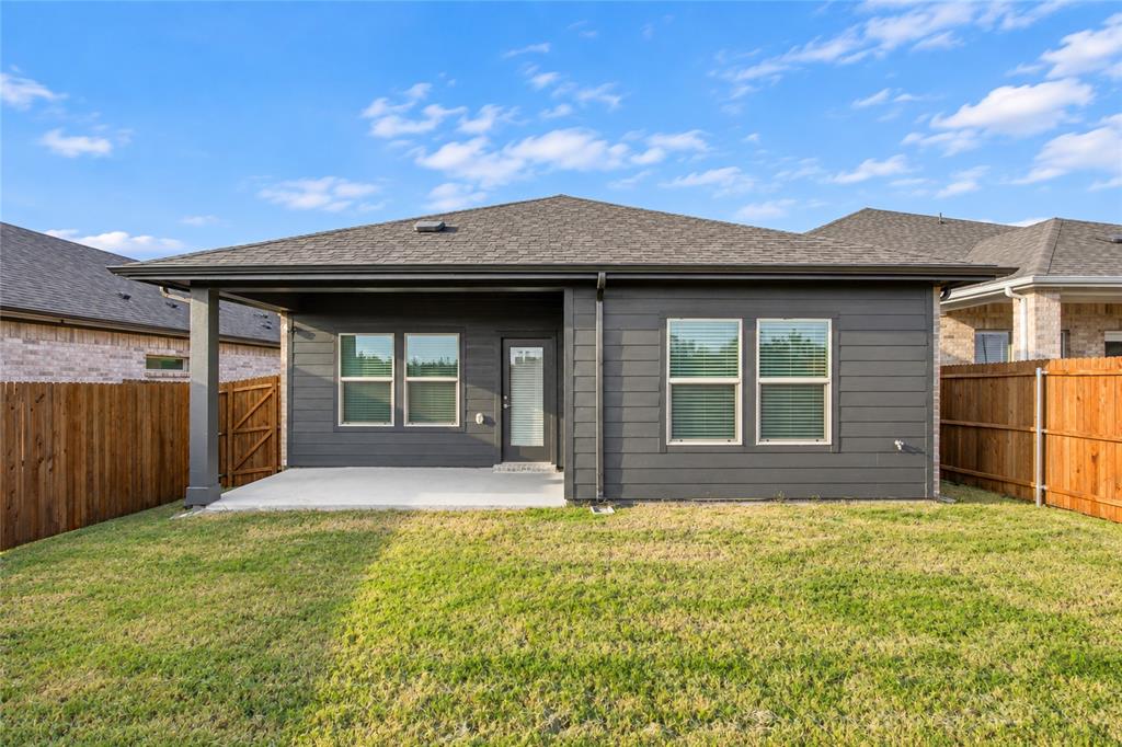 Spacious backyard with a covered patio, dark gray siding, and a wooden privacy fence
