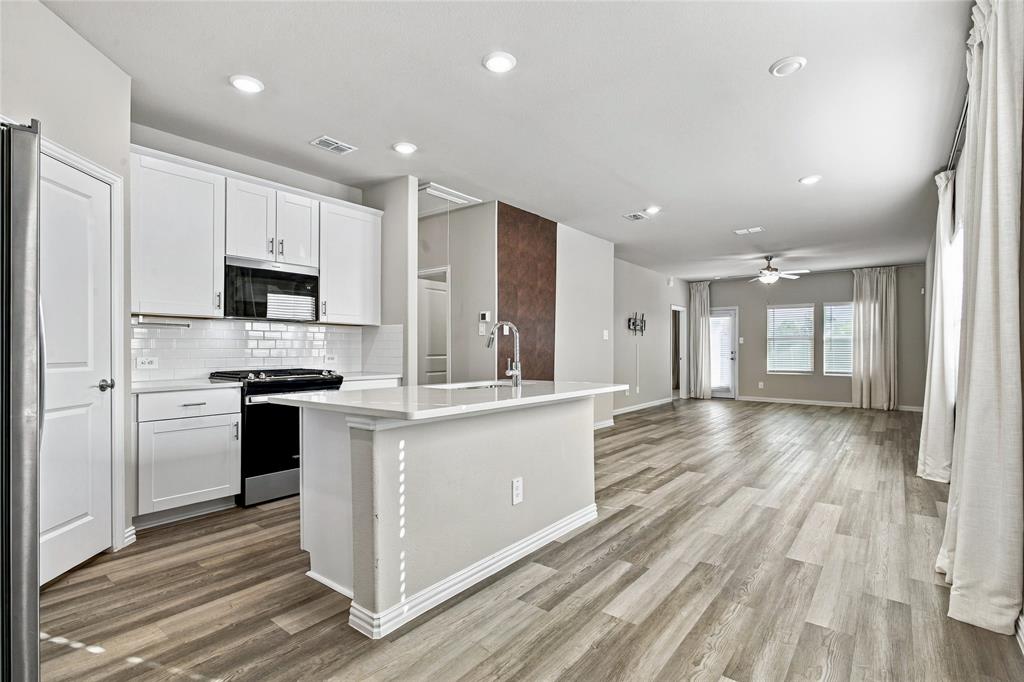 Kitchen featuring white shaker cabinetry, subway tile backsplash, and a central island