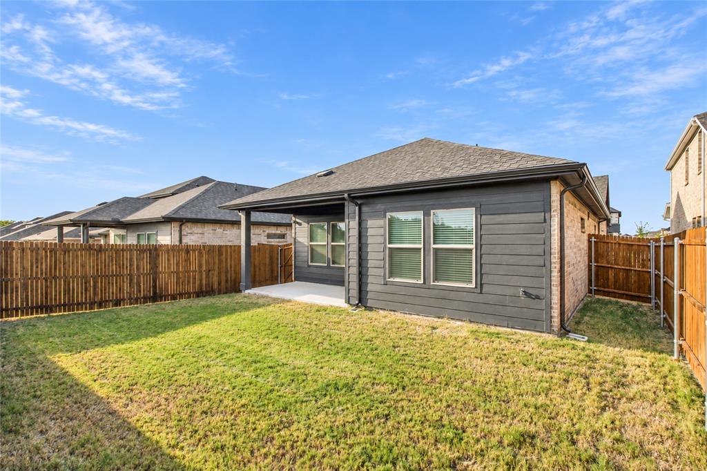 Backyard featuring a covered patio, wood privacy fencing, and a manicured lawn