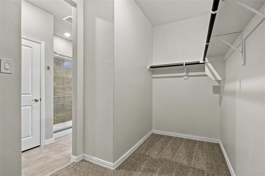 Carpeted closet space with multiple hanging rods and shelving