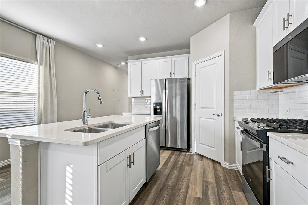 Kitchen with white cabinetry, stainless steel appliances, wood-finish flooring, and recessed lighting