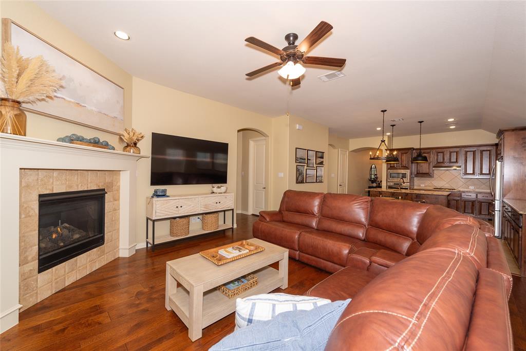 Spacious living room featuring a custom leather sectional sofa, wood-finish flooring, and a gas fireplace with tile surround