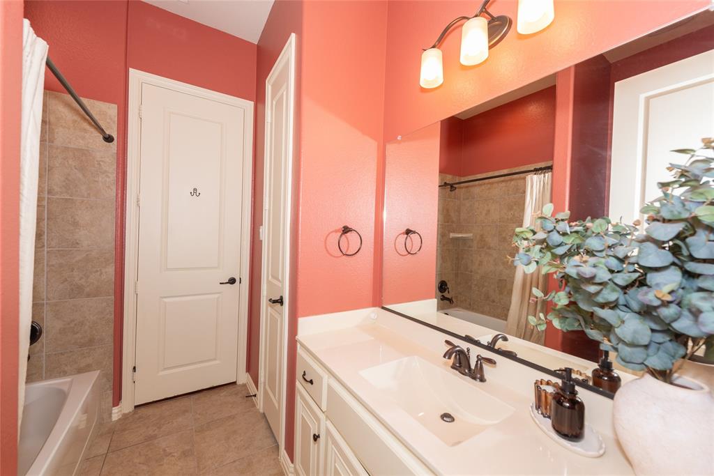 Bathroom featuring a single vanity with a solid surface countertop, an undermount sink, and a framed mirror