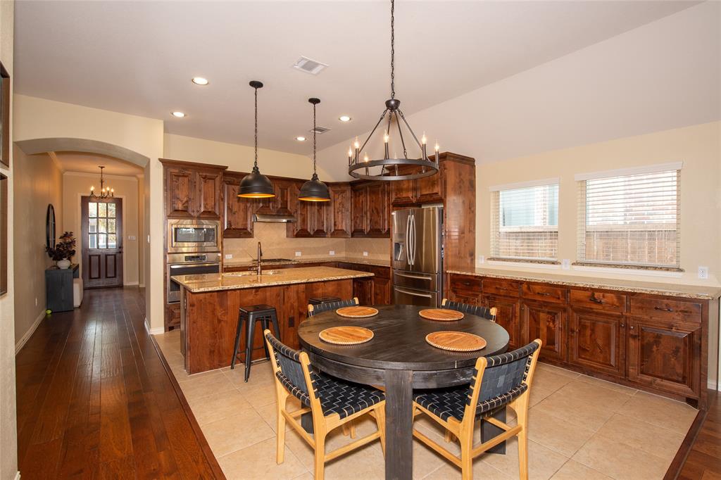 Kitchen with wood-finish cabinetry, stainless steel appliances, a center island with sink, and tile flooring Kitchen with wood-finish cabinetry, stainless steel appliances, a center island with sink, and tile flooring