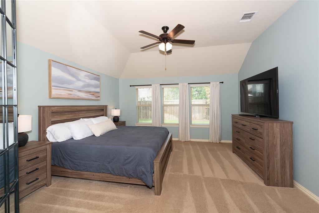 Vaulted ceiling, three windows, ceiling fan, wood-finish flooring, and light blue wall color