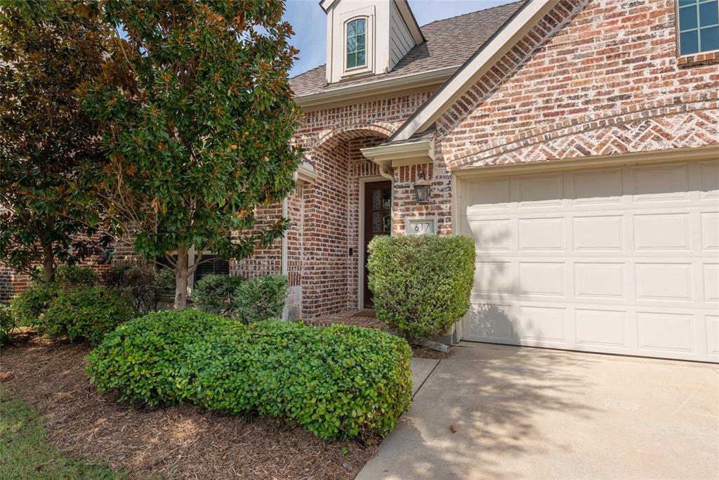 Brick exterior with an arched entryway, dormer window, and an attached garage