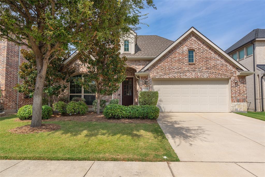 Brick facade with stone accents, a gabled roofline, an attached garage, a concrete driveway, and established front landscaping Brick facade with stone accents, a gabled roofline, an attached garage, a concrete driveway, and established front landscaping