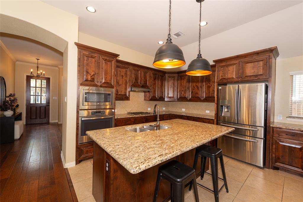 Kitchen featuring wood cabinetry, stainless steel appliances, an island with an undermount sink, and recessed lighting Kitchen featuring wood cabinetry, stainless steel appliances, an island with an undermount sink, and recessed lighting