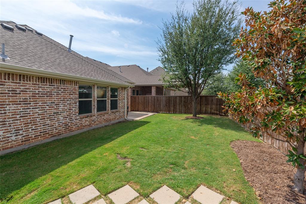Expansive backyard featuring a manicured lawn, established trees, and a privacy fence