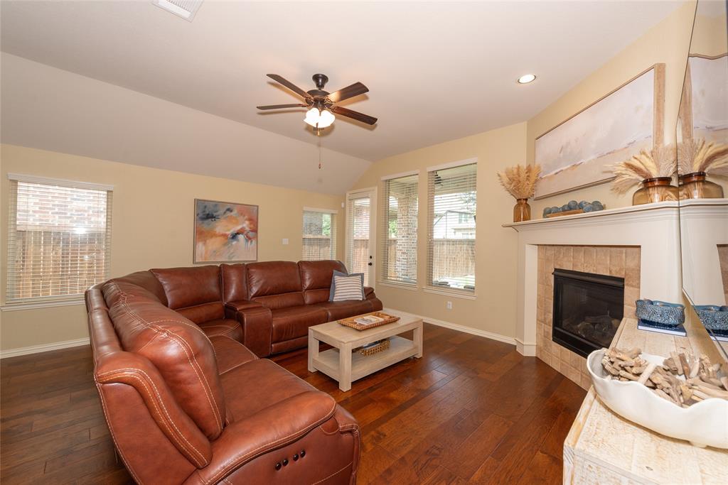 Vaulted ceiling featuring a ceiling fan, recessed lighting, wood-finish flooring, and a fireplace with a tile surround and mantel