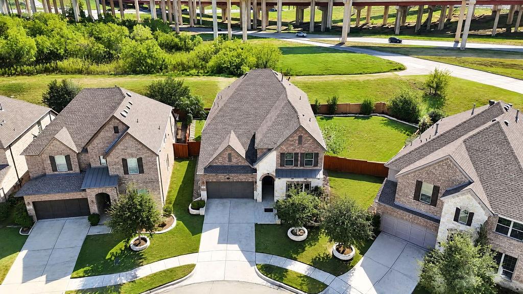 Multi-story brick and stone facade, attached two-car garage, steep-pitched roofline, and manicured front lawn