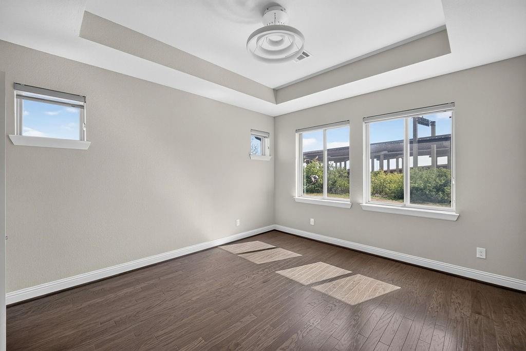 Tray ceiling, dark wood-finish flooring, multi-pane windows, and modern flush-mount overhead lighting