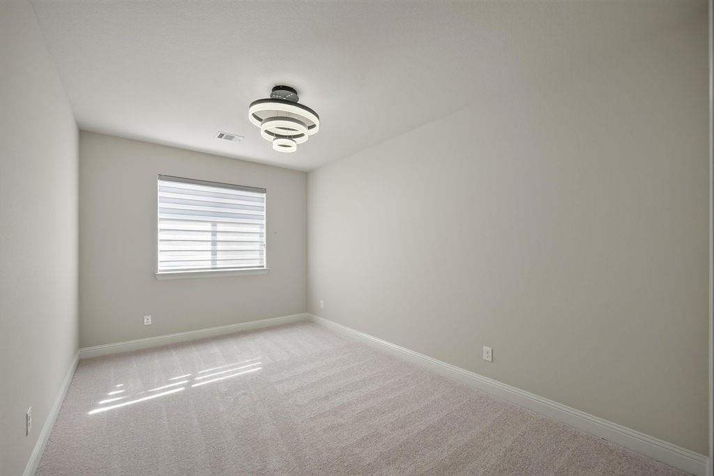 Neutral-toned interior featuring wall-to-wall carpeting, a contemporary tiered flush-mount light fixture, and a window with horizontal shades