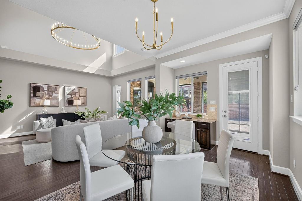 Vaulted ceilings, wood-finish flooring, built-in wet bar, and decorative chandeliers