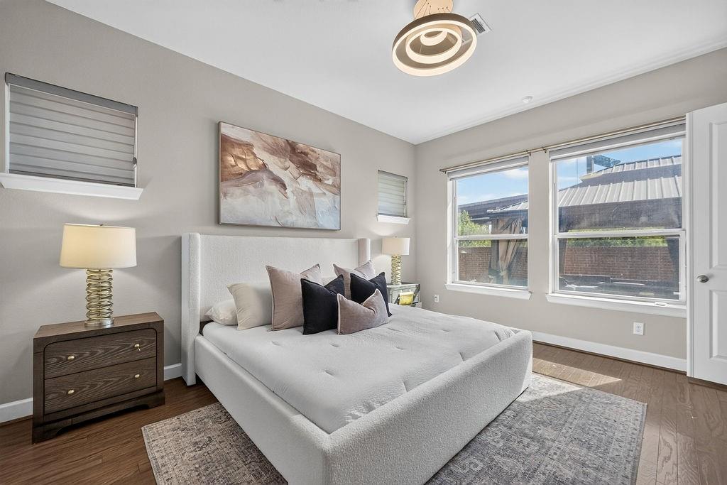 Neutral-toned walls featuring wood-finish flooring, dual windows, and a modern circular semi-flush mount light fixture