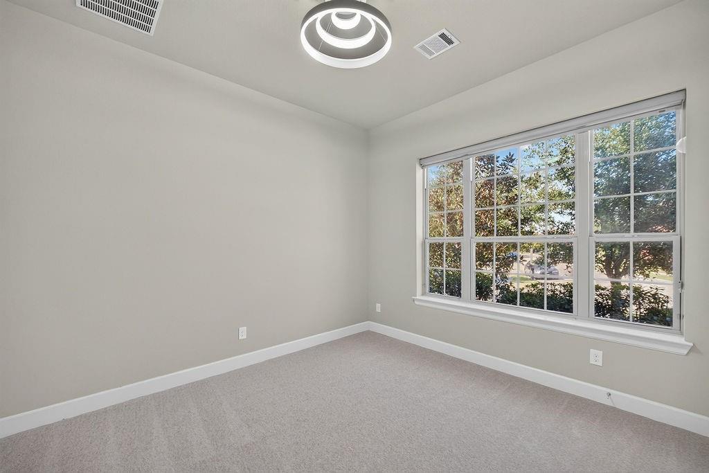 Neutral-toned interior featuring multi-pane windows, wall-to-wall carpeting, and a contemporary tiered ceiling fixture
