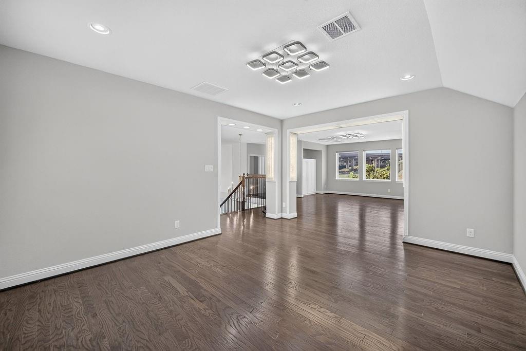 Interior space featuring dark wood-finish flooring, vaulted ceilings, recessed lighting, and a contemporary geometric flush-mount light fixture