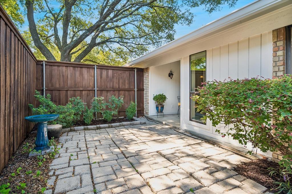 Paved patio with decorative pavers, flanked by a full wood fence and established landscaping