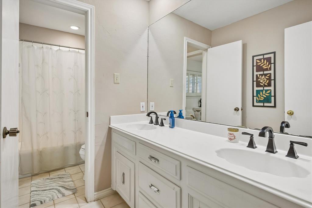 Dual vanity with white cabinetry, solid surface countertop, and dark-finish hardware