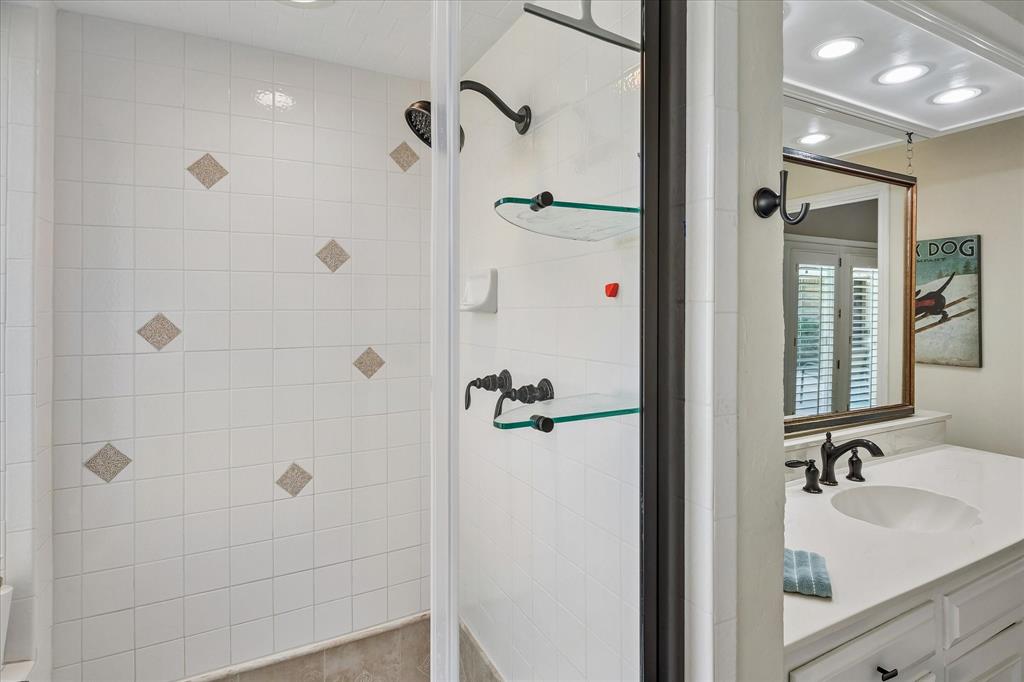 White tiled shower with decorative accent tiles, framed glass shower enclosure, and dark bronze fixtures