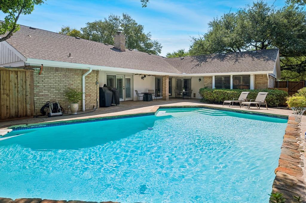 Expansive outdoor patio with a built-in swimming pool, integrated steps, and a stone-capped pool edge