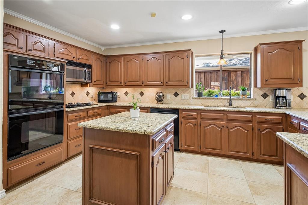 Kitchen featuring wood cabinetry, granite countertops, tile flooring, a built-in double oven, and a central island