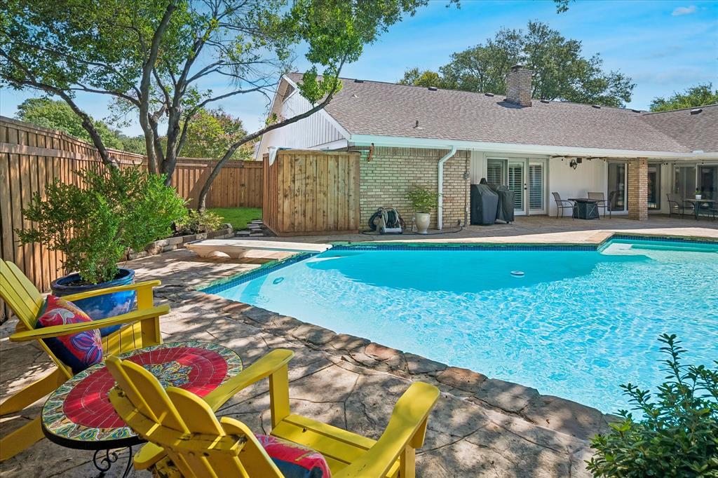 Swimming pool with stone coping, a paved deck, wood privacy fence and green space
