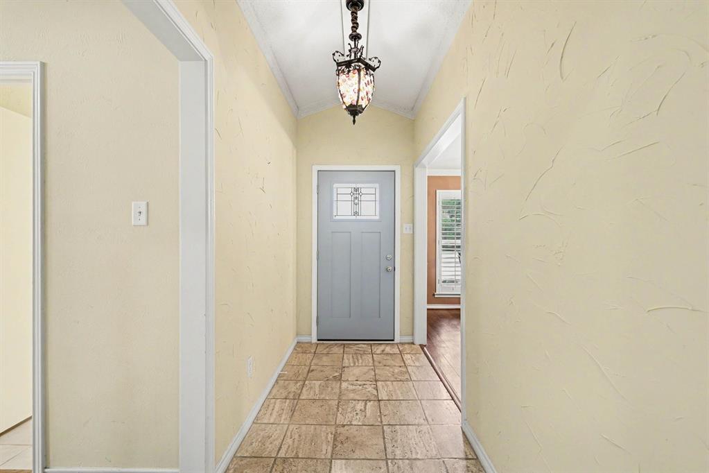 Vaulted ceiling with an ornamental chandelier, textured wall finish, and tile flooring Vaulted ceiling with an ornamental chandelier, textured wall finish, and tile flooring